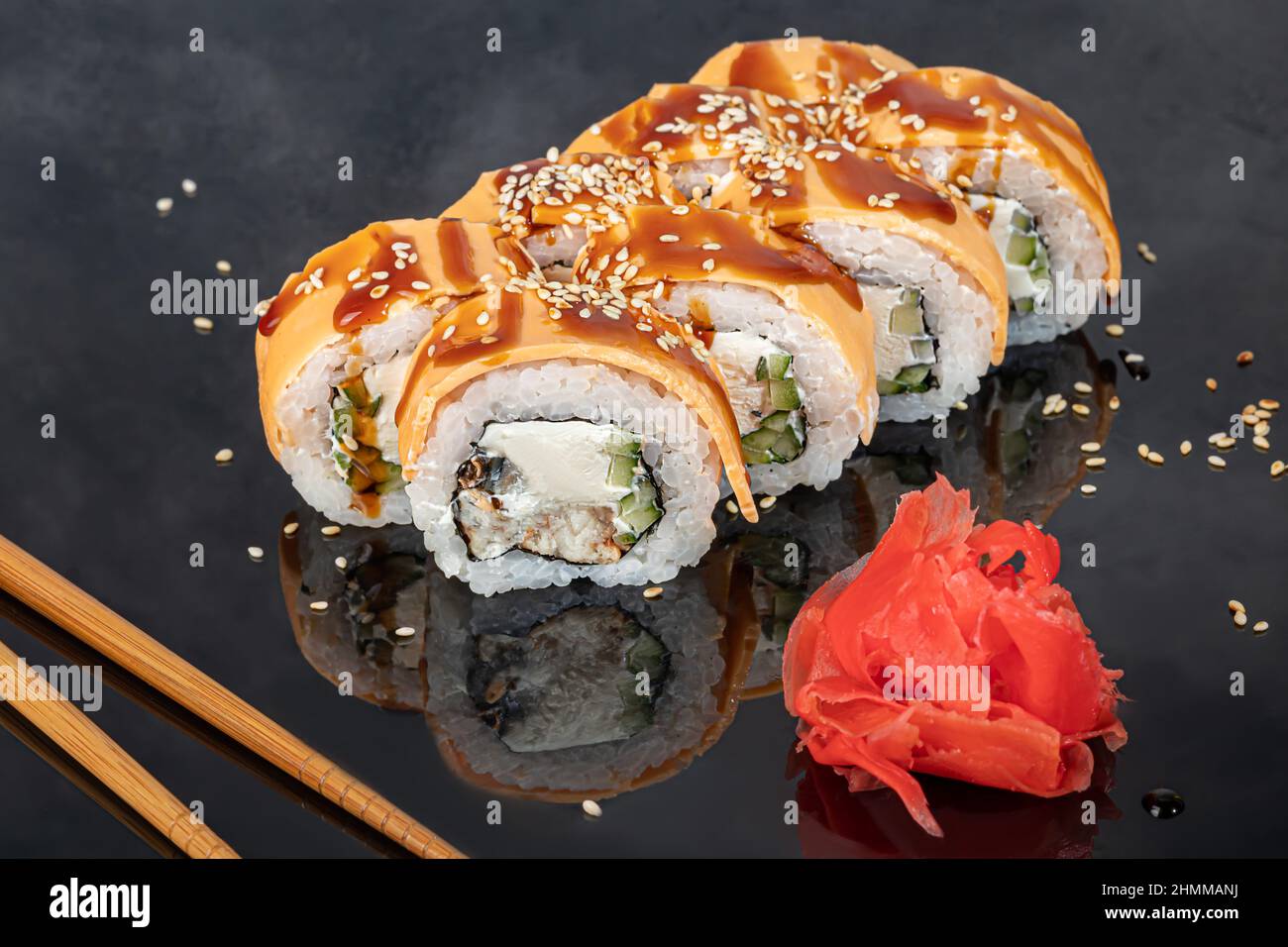 Sushi-Sets Uramaki, California, Philadelphia, Rollen auf einem weißen Teller. Menü für Restaurants, Cafés. Auf einem dunklen reflektierenden Hintergrund Stockfoto
