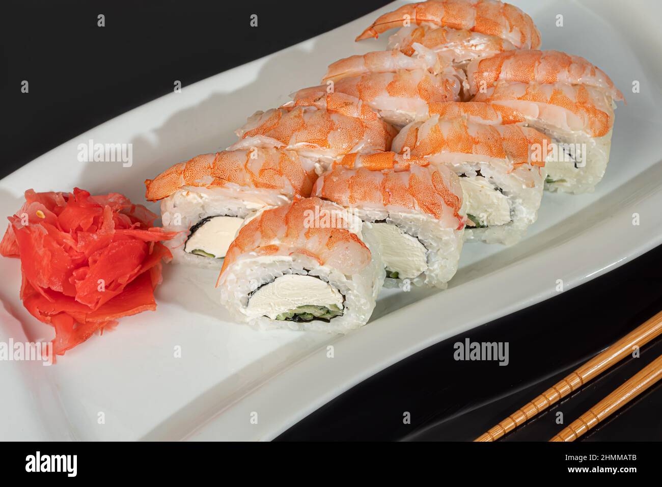 Sushi-Sets Uramaki, California, Philadelphia, Rollen auf einem weißen Teller. Menü für Restaurants, Cafés. Auf einem dunklen reflektierenden Hintergrund Stockfoto