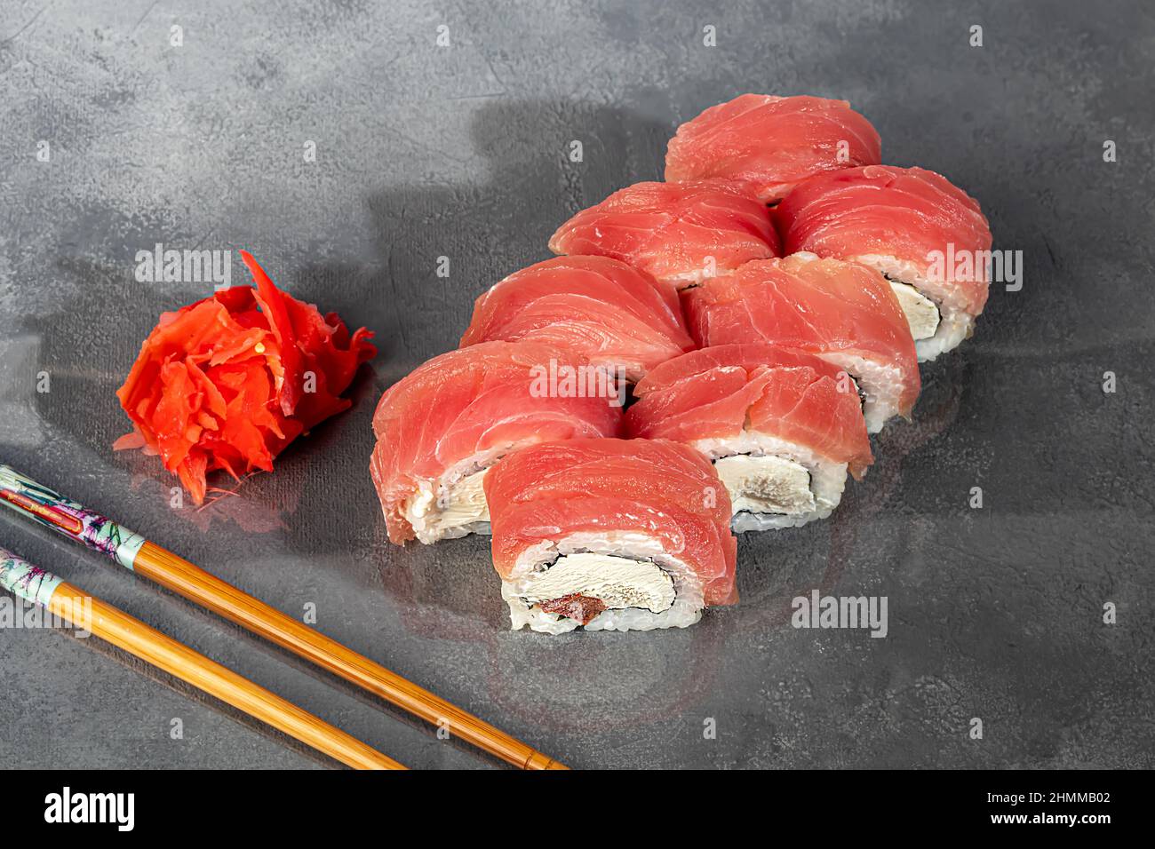 Sushi-Sets Uramaki, California, Philadelphia, Rollen auf einem weißen Teller. Menü für Restaurants, Cafés. Auf einem dunklen reflektierenden Hintergrund Stockfoto