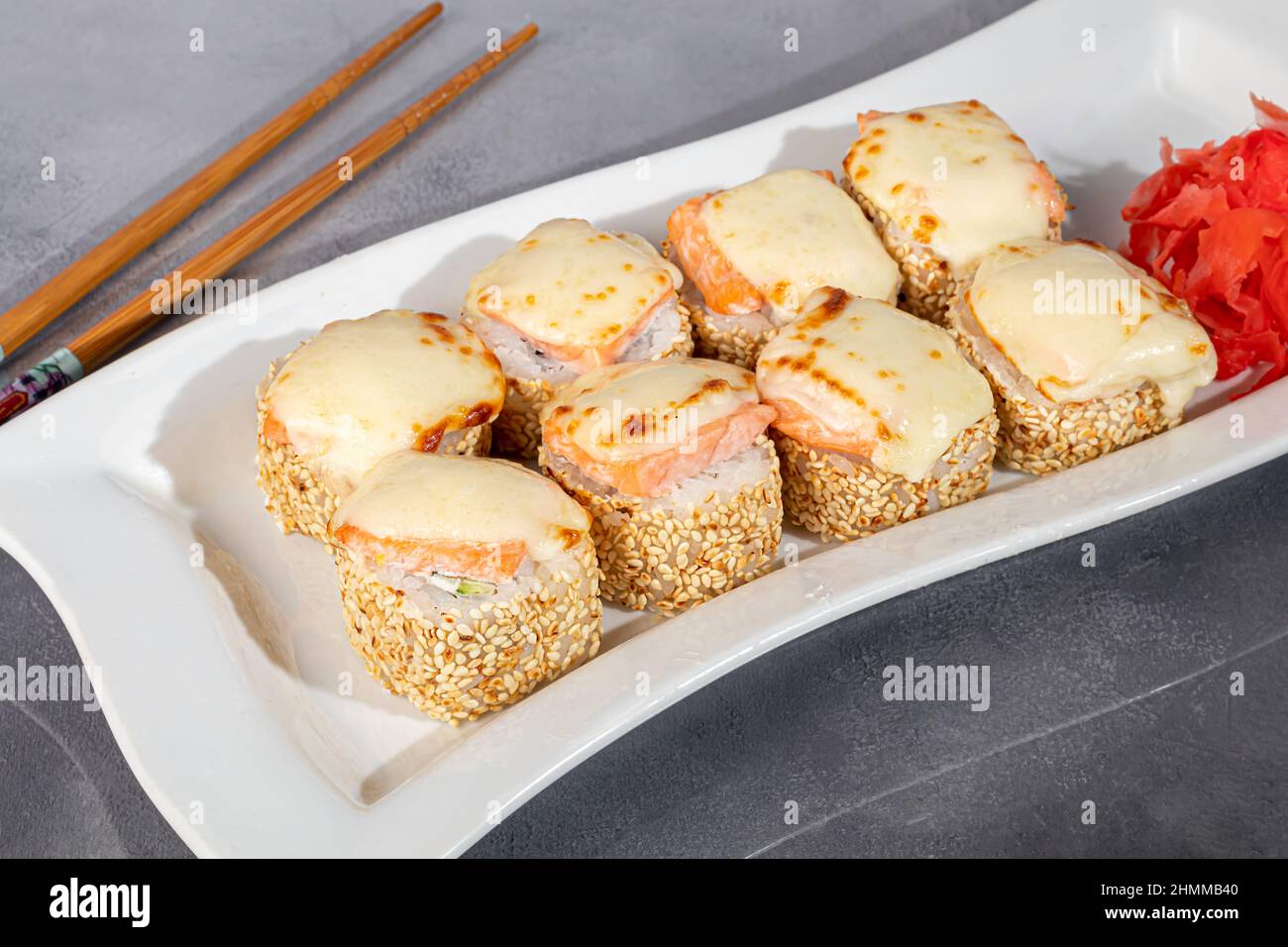 Sushi-Sets Uramaki, California, Philadelphia, Rollen auf einem weißen Teller. Menü für Restaurants, Cafés. Auf einem dunklen reflektierenden Hintergrund Stockfoto