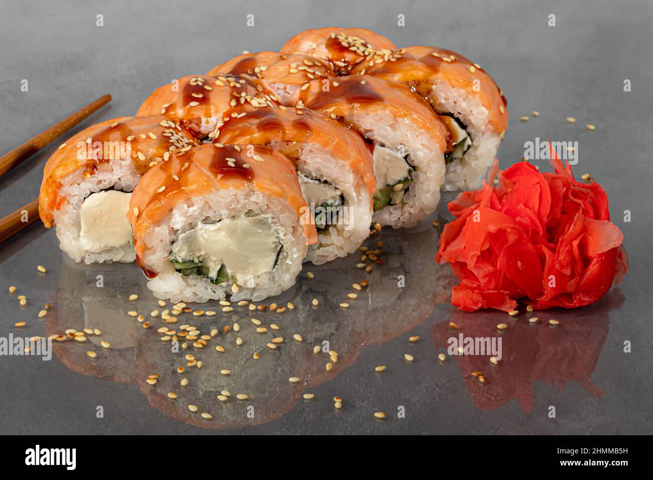 Sushi-Sets Uramaki, California, Philadelphia, Rollen auf einem weißen Teller. Menü für Restaurants, Cafés. Auf einem dunklen reflektierenden Hintergrund Stockfoto
