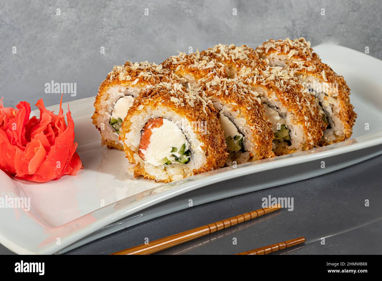 Sushi-Sets Uramaki, California, Philadelphia, Rollen auf einem weißen Teller. Menü für Restaurants, Cafés. Auf einem dunklen reflektierenden Hintergrund Stockfoto
