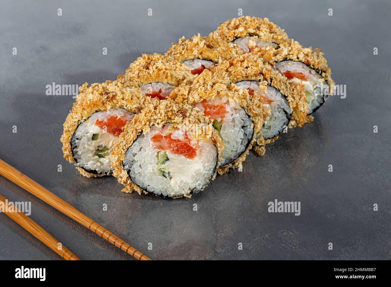 Sushi-Sets Uramaki, California, Philadelphia, Rollen auf einem weißen Teller. Menü für Restaurants, Cafés. Auf einem dunklen reflektierenden Hintergrund Stockfoto