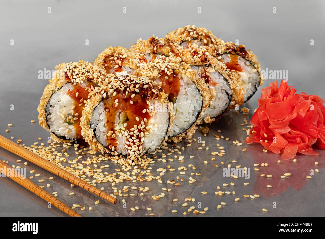 Sushi-Sets Uramaki, California, Philadelphia, Rollen auf einem weißen Teller. Menü für Restaurants, Cafés. Auf einem dunklen reflektierenden Hintergrund Stockfoto