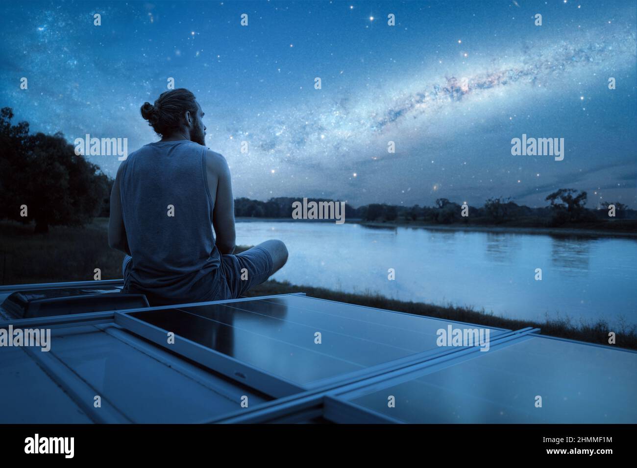 Mann, der eine sternenklare Nacht vom Dach seines Wohnwagens aus beobachtet Stockfoto