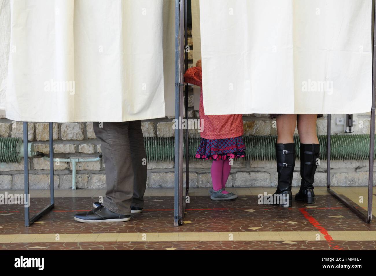 Saint-Etienne-du-Rouvray (Nordfrankreich): Kommunalwahlen, erste Runde im März 2014, Wahllokal. Kleines Mädchen mit ihrer Mutter in einer Zugkabine und Mann in einer anderen Stockfoto