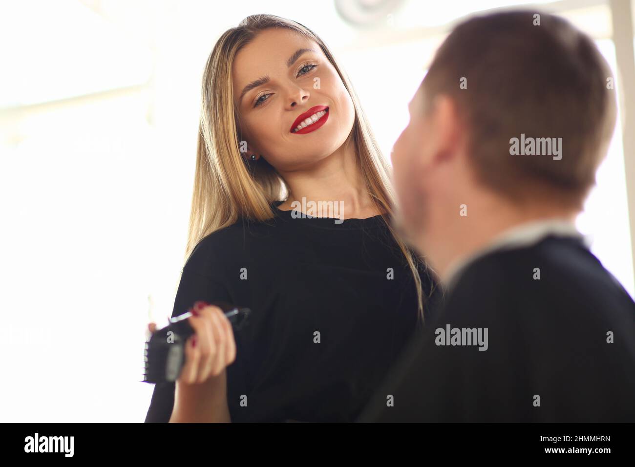 Friseur Frau kommuniziert mit männlichen Kunden im Friseursalon Stockfoto