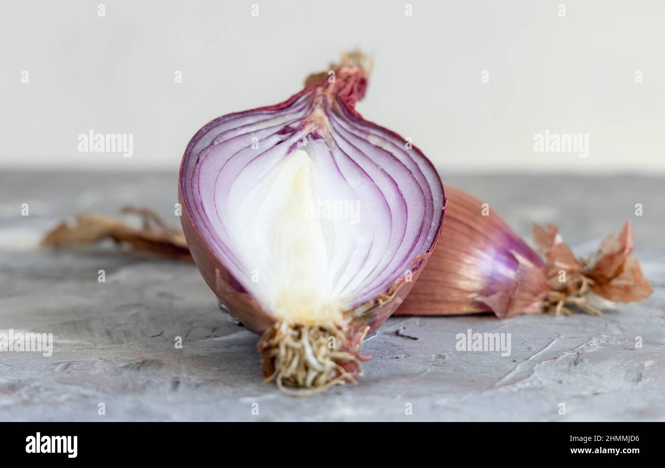 Die Hälfte der roten tropea Zwiebeln auf einem grauen Tisch aus der Nähe. Traditionelles süditalienisches Gemüse aus der Region. Kochvorgang in der heimischen Küche Stockfoto