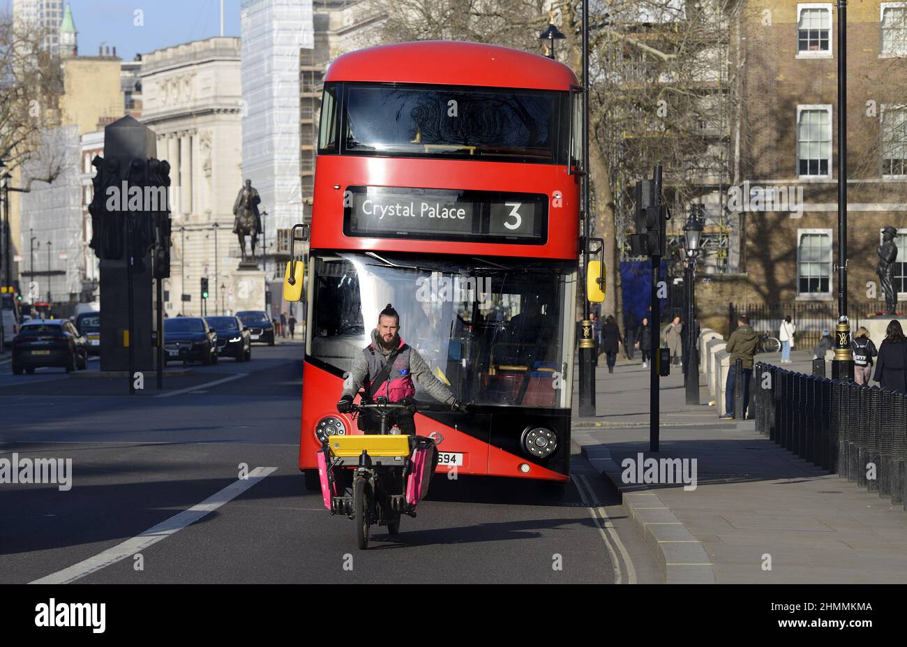 London, England, Großbritannien. Fahrrad liefern Fahrer vor einem Bus, Whitehall, Westminster Stockfoto