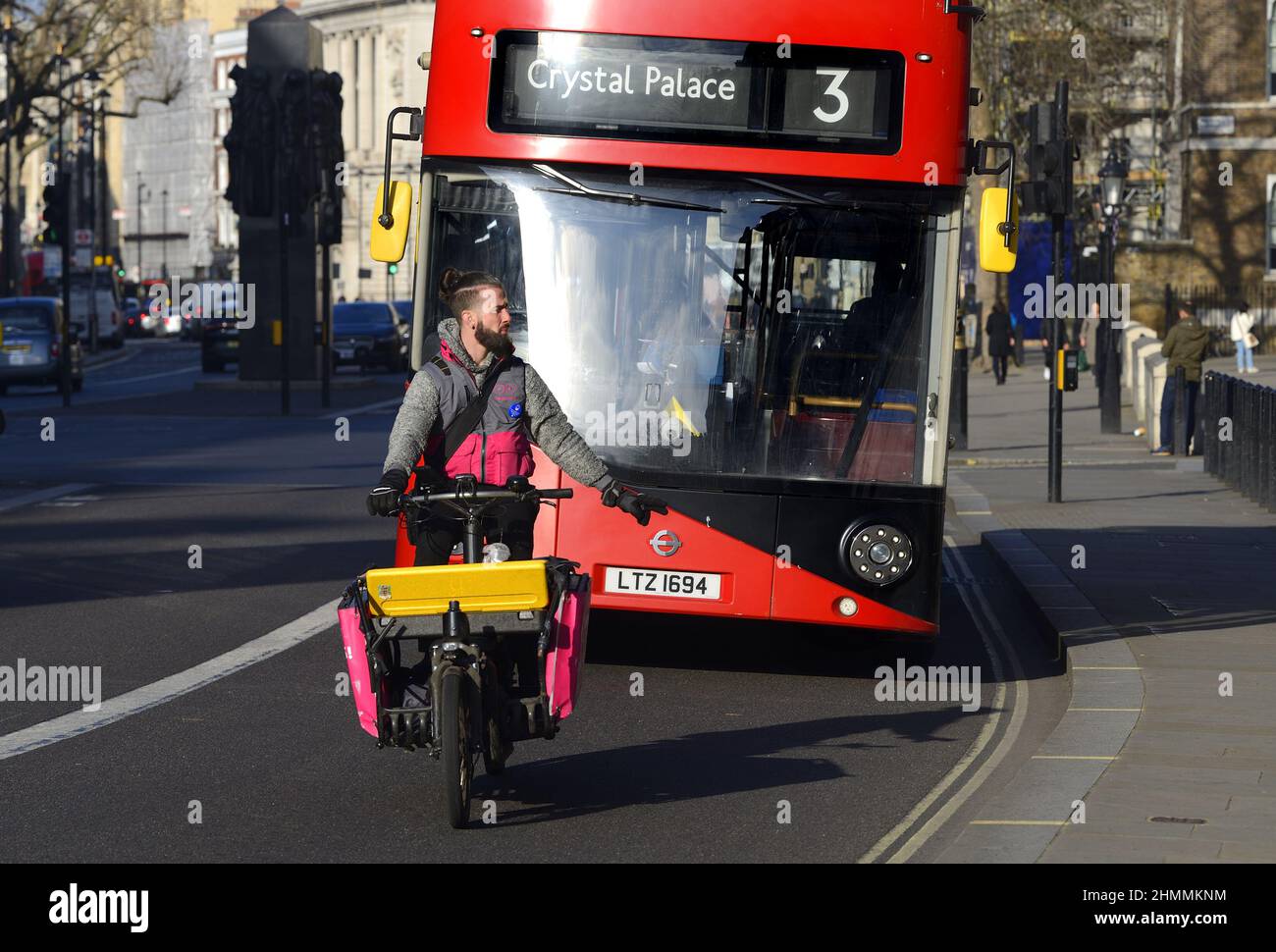 London, England, Großbritannien. Fahrrad liefern Fahrer vor einem Bus, Whitehall, Westminster Stockfoto