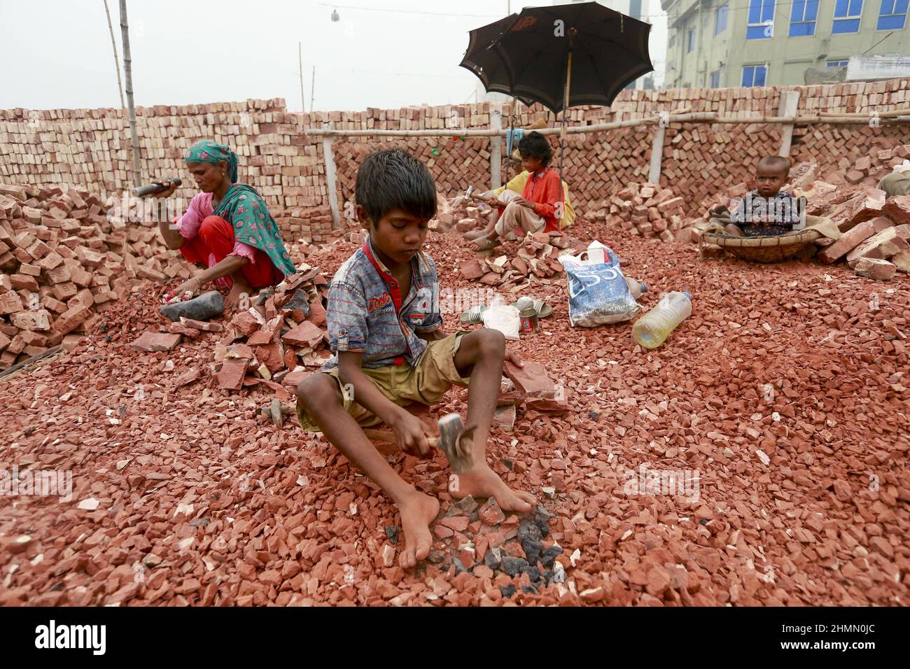Ramjan, 8, Kinder aus Bangladesch, brechen Ziegel, die als Kies für den Bau in Dhaka, Bangladesch, verwendet werden sollen, 10. Februar 2022. Kinderarbeit ist in Bangladesch üblich, 4,7 Millionen Kinder im Alter von 5 bis 14 Jahren arbeiten in der Belegschaft. Von den Kinderarbeitern, die in der Belegschaft beschäftigt sind, sind 83 % in ländlichen Gebieten und 17 % in städtischen Gebieten beschäftigt. Im Jahr 2006 verabschiedete Bangladesch ein Arbeitsgesetz, in dem das Mindestalter für eine Beschäftigung auf 14 Jahre festgelegt wurde. Dennoch ist die Durchsetzung solcher Arbeitsgesetze in Bangladesch praktisch unmöglich, da 93 % der Kinderarbeiter im informellen Sektor wie Smal beschäftigt sind Stockfoto