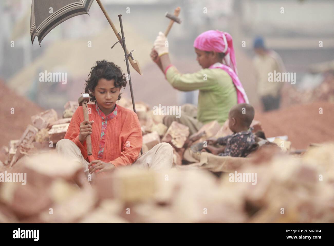 Die Kinder von Bangladesch, Rajiya, 9, brechen Ziegel, die als Kies für den Bau in Dhaka, Bangladesch, verwendet werden sollen, 10. Februar 2022. Kinderarbeit ist in Bangladesch üblich, 4,7 Millionen Kinder im Alter von 5 bis 14 Jahren arbeiten in der Belegschaft. Von den Kinderarbeitern, die in der Belegschaft beschäftigt sind, sind 83 % in ländlichen Gebieten und 17 % in städtischen Gebieten beschäftigt. Im Jahr 2006 verabschiedete Bangladesch ein Arbeitsgesetz, in dem das Mindestalter für eine Beschäftigung auf 14 Jahre festgelegt wurde. Dennoch ist die Durchsetzung solcher Arbeitsgesetze in Bangladesch praktisch unmöglich, da 93 % der Kinderarbeiter im informellen Sektor wie Smal beschäftigt sind Stockfoto