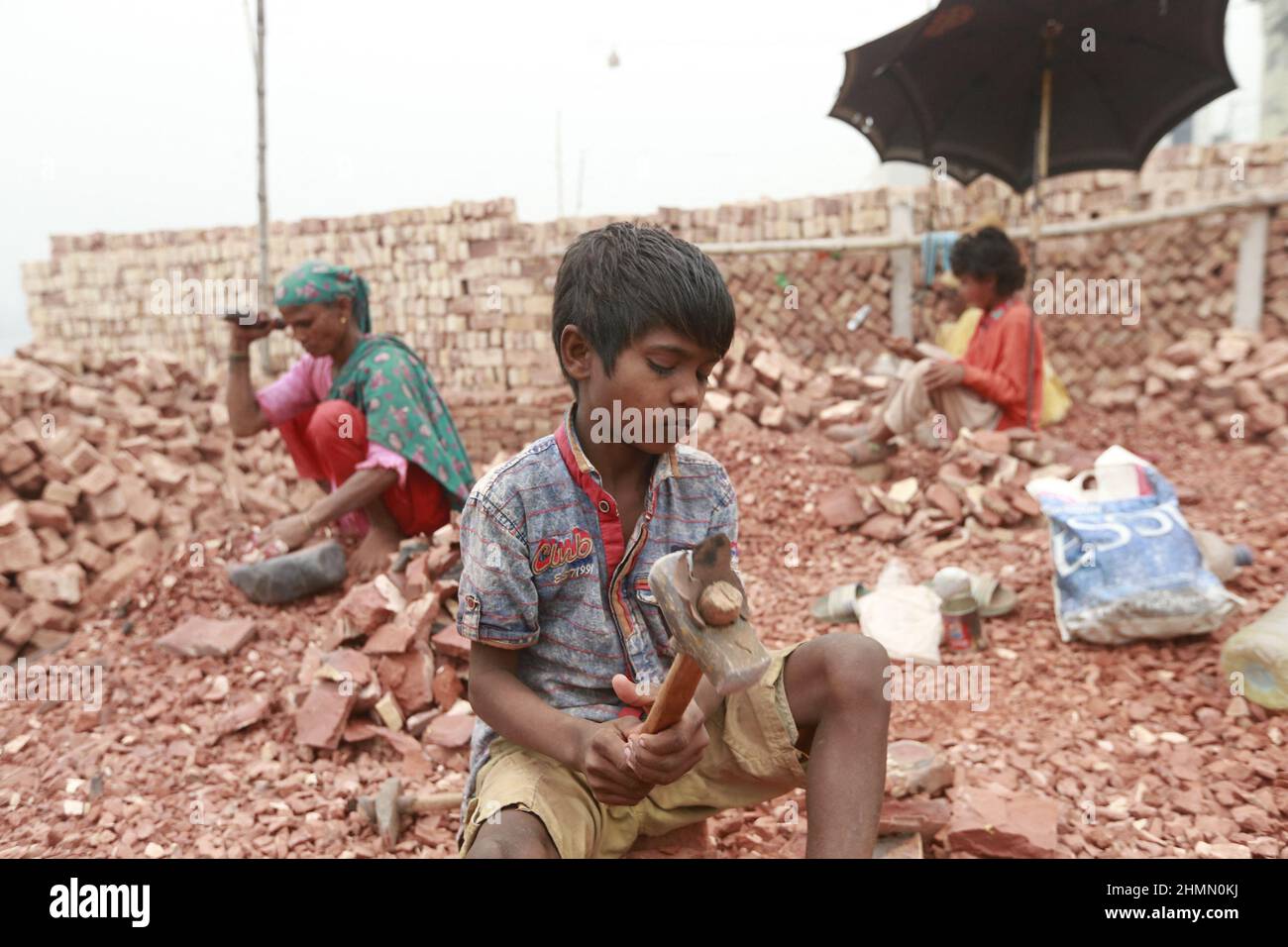 Ramjan, 8, Kinder aus Bangladesch, brechen Ziegel, die als Kies für den Bau in Dhaka, Bangladesch, verwendet werden sollen, 10. Februar 2022. Kinderarbeit ist in Bangladesch üblich, 4,7 Millionen Kinder im Alter von 5 bis 14 Jahren arbeiten in der Belegschaft. Von den Kinderarbeitern, die in der Belegschaft beschäftigt sind, sind 83 % in ländlichen Gebieten und 17 % in städtischen Gebieten beschäftigt. Im Jahr 2006 verabschiedete Bangladesch ein Arbeitsgesetz, in dem das Mindestalter für eine Beschäftigung auf 14 Jahre festgelegt wurde. Dennoch ist die Durchsetzung solcher Arbeitsgesetze in Bangladesch praktisch unmöglich, da 93 % der Kinderarbeiter im informellen Sektor wie Smal beschäftigt sind Stockfoto