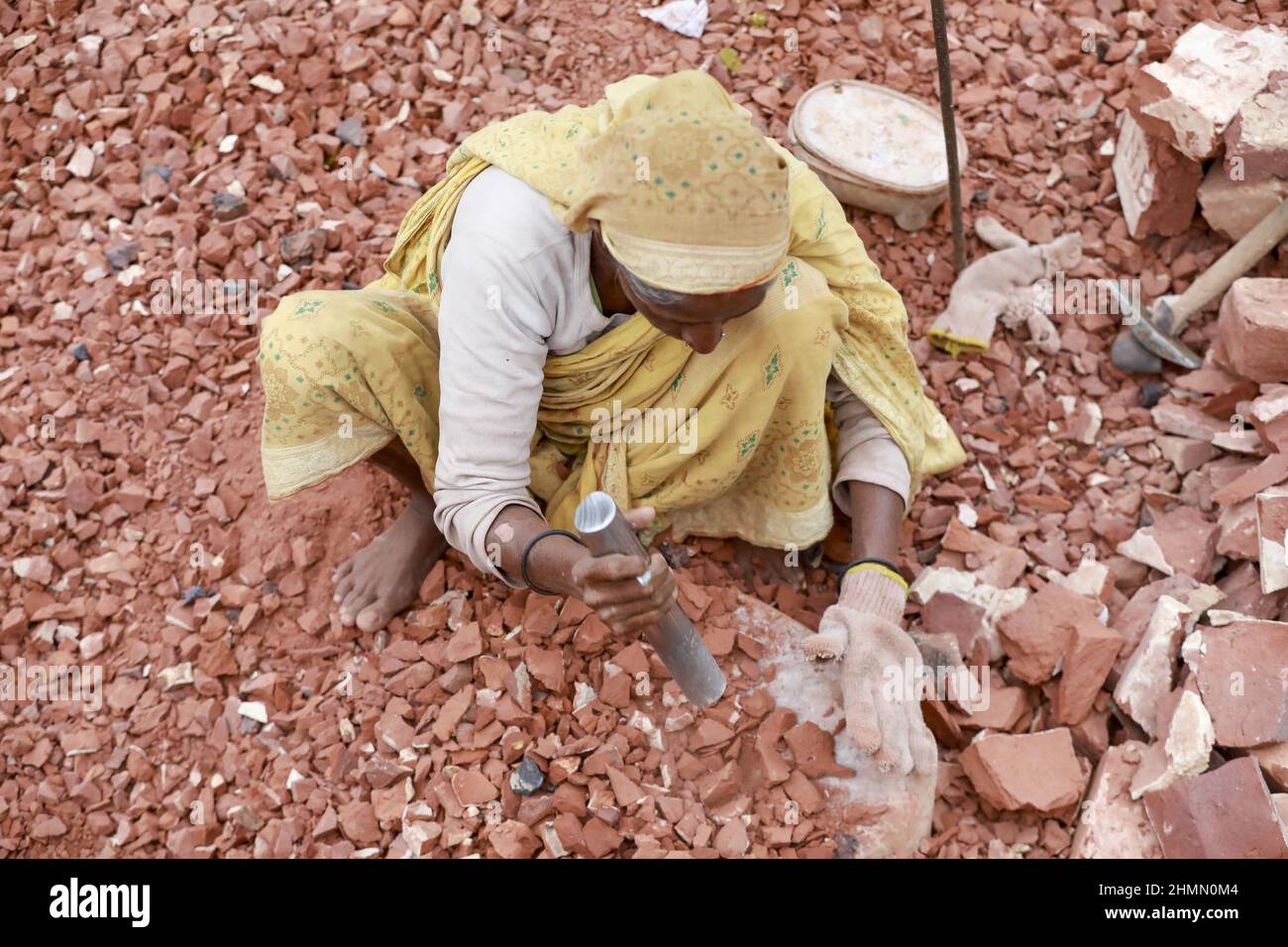 Eine bangladeschische Frau bricht Ziegel, um als Kies für den Bau in Dhaka, Bangladesch, verwendet zu werden, 10. Februar 2022. Kinderarbeit ist in Bangladesch üblich, 4,7 Millionen Kinder im Alter von 5 bis 14 Jahren arbeiten in der Belegschaft. Von den Kinderarbeitern, die in der Belegschaft beschäftigt sind, sind 83 % in ländlichen Gebieten und 17 % in städtischen Gebieten beschäftigt. Im Jahr 2006 verabschiedete Bangladesch ein Arbeitsgesetz, in dem das Mindestalter für eine Beschäftigung auf 14 Jahre festgelegt wurde. Dennoch ist die Durchsetzung solcher Arbeitsgesetze in Bangladesch praktisch unmöglich, da 93 % der Kinderarbeiter im informellen Sektor wie in kleinen Fabriken beschäftigt sind Stockfoto