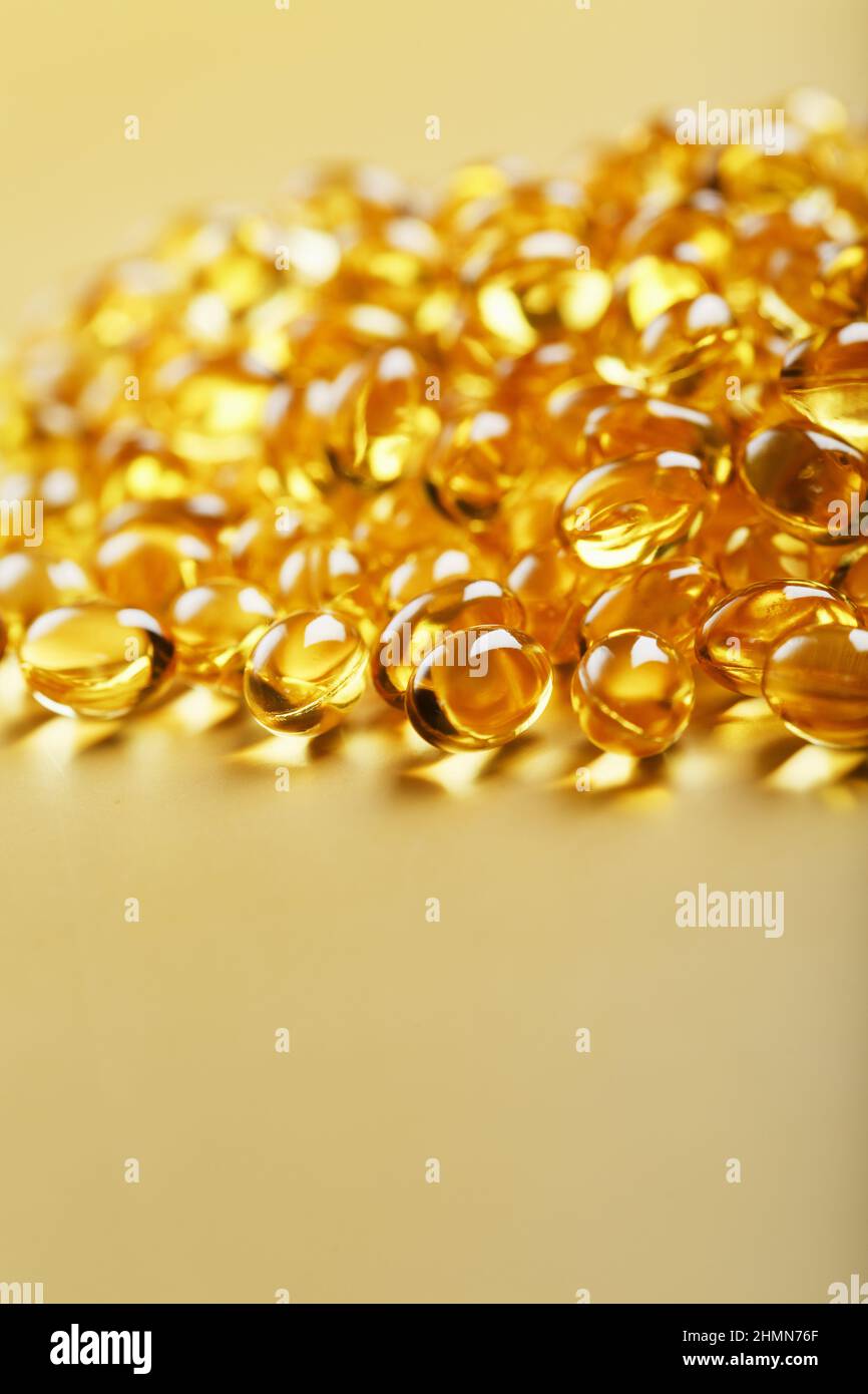 Haufen goldener Kapseln von Vitamin D3 auf gelbem Hintergrund mit freiem Platz. Biologisch aktive Substanzen der Calciferol-Gruppe sind fettlöslich o Stockfoto