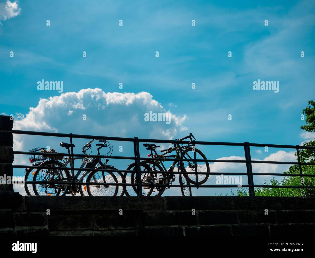Vier Fahrräder parkten in der Nähe von Metallzaun auf einem blauen Himmel Hintergrund Stockfoto
