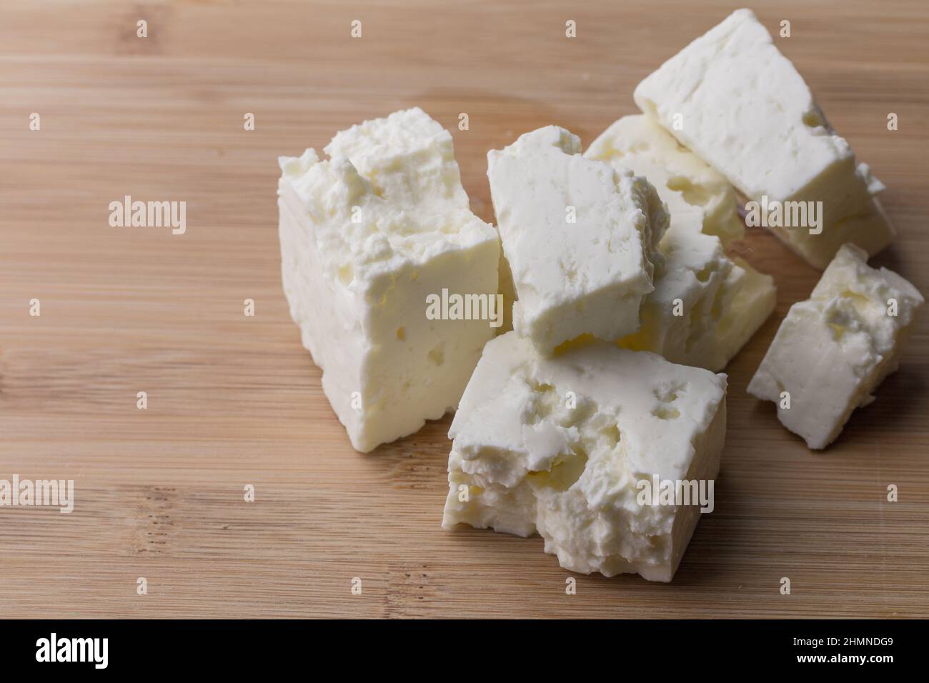 Weiche weiße Käsewürfel auf Holzbrett mit Kopierfläche - Feta-Käse Stockfoto