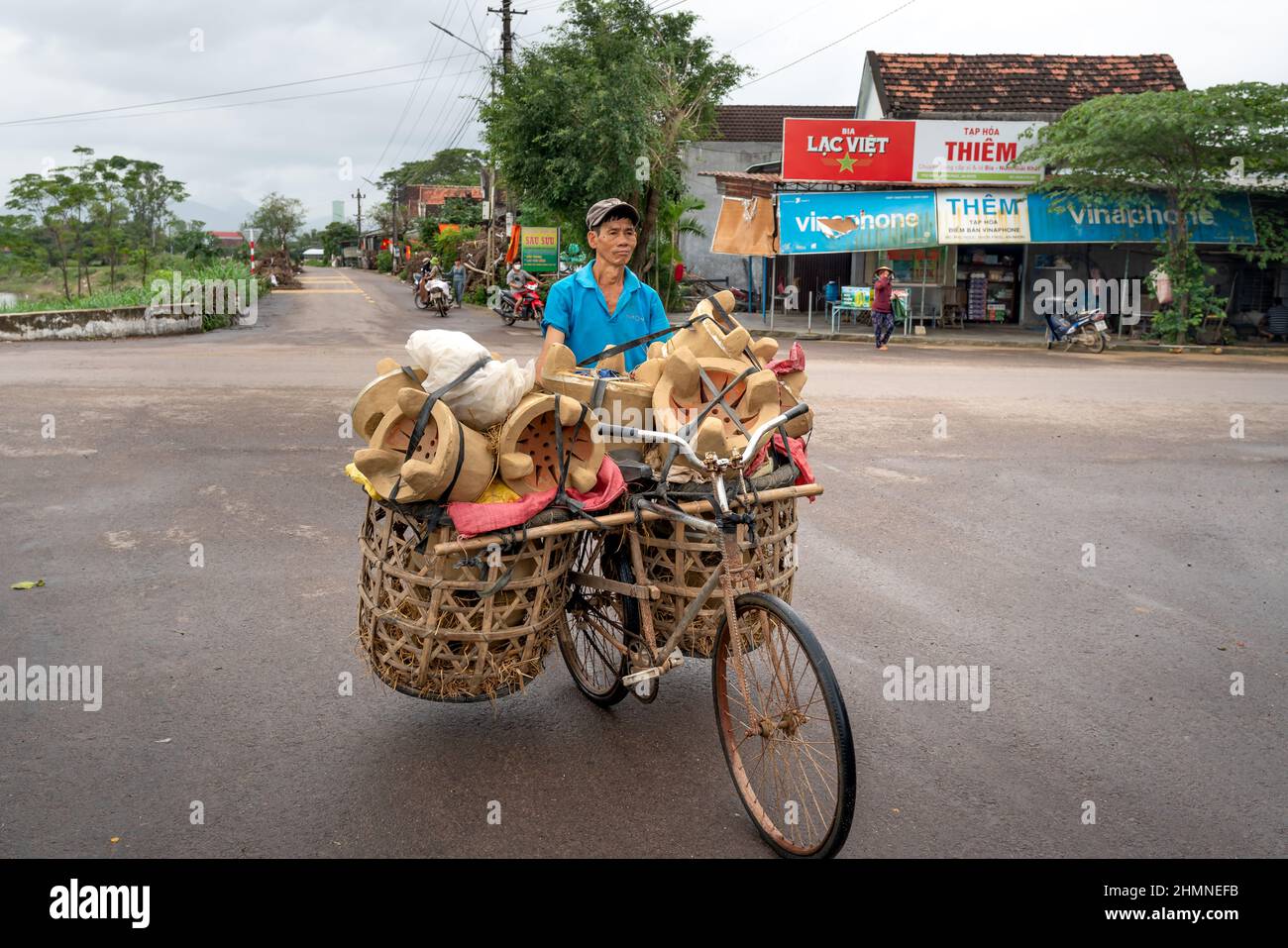 Provinz Binh Dinh, Vietnam - 3. Januar 2022: Ein Landwirt verkauft handgefertigte Öfen, die auf einem alten Fahrrad in der Provinz Binh Dinh, Vietnam, transportiert werden Stockfoto
