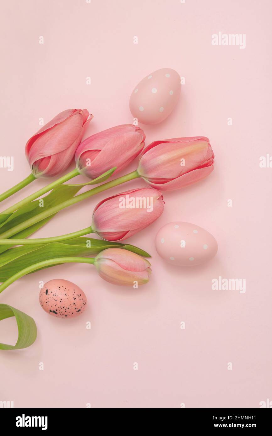 Frohe Ostern Grußkarte. Pastellfarbe Ei und Tulpe Blumenstrauß auf rosa Hintergrund, Draufsicht, kopieren Raum. Frühlingsfeiertage Stockfoto