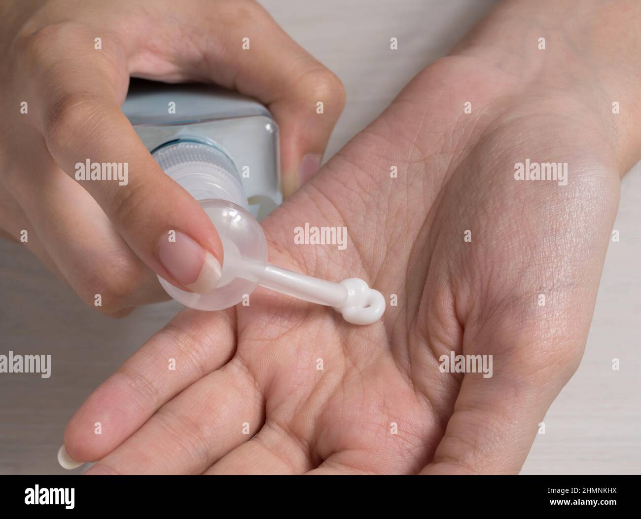 Frau hält die Cremeböhre und wendet Feuchtigkeitscreme auf ihre schönen Hände an, um eine saubere und weiche Haut zu erhalten. Weißer Hintergrund. Achten Sie auf Ihre Körperhaut. Stockfoto