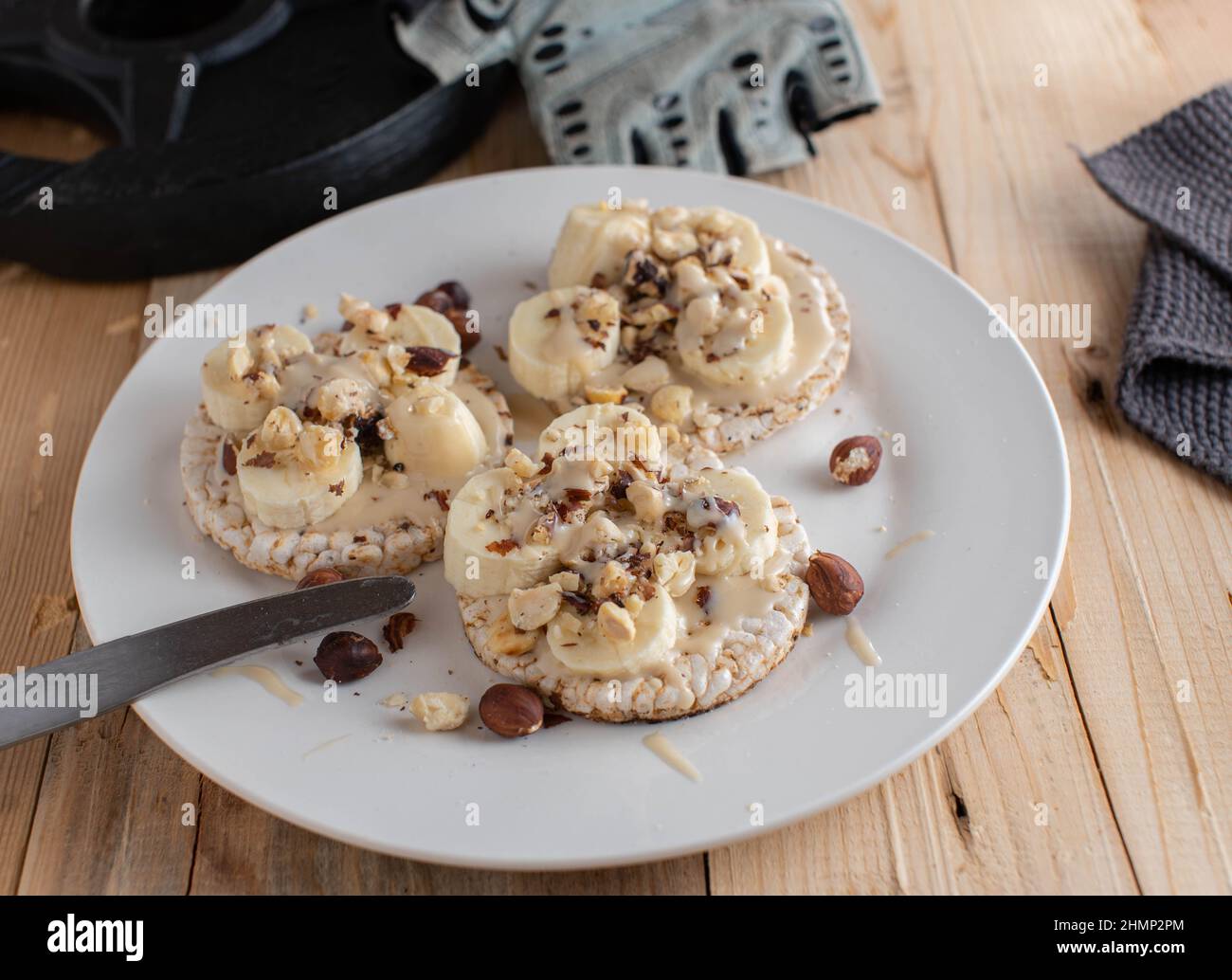 Reiskracker mit Mandelbutter, Bananen und Haselnüssen anbraten. Gesunde Energie Frühstück oder Snack Stockfoto