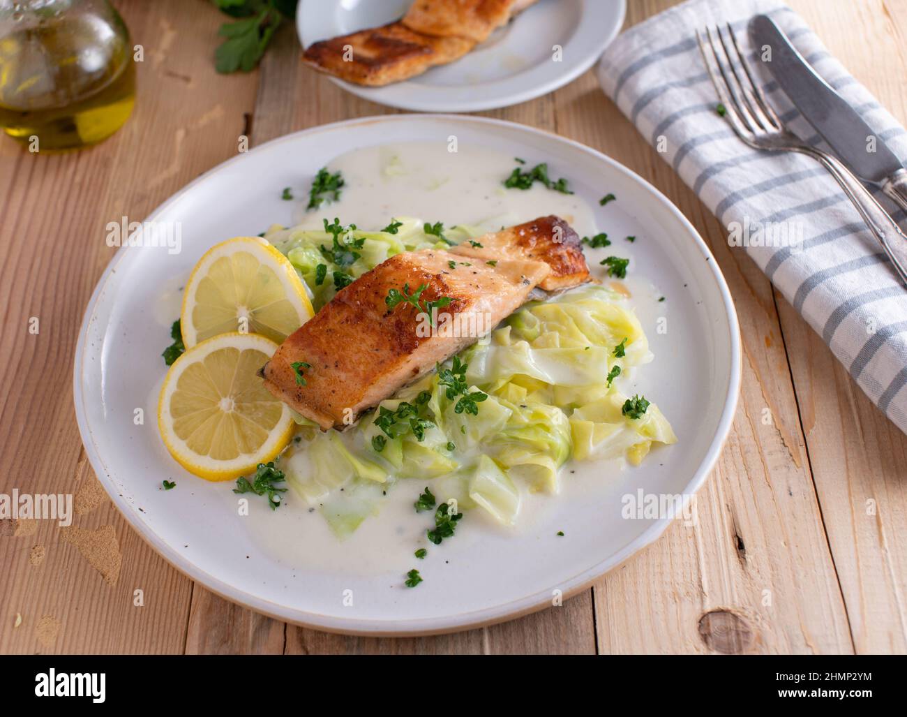 Fischgericht mit Gemüse. Gebratenes Lachsfilet mit Kohl und Bechamelsauce auf einem weißen Teller. Stockfoto
