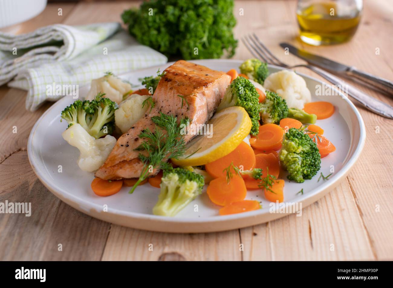 Kohlenhydratarme Fischgerichte mit gebratenem Lachsfilet, serviert mit kaiserlichem Gemüse auf einem Teller Stockfoto