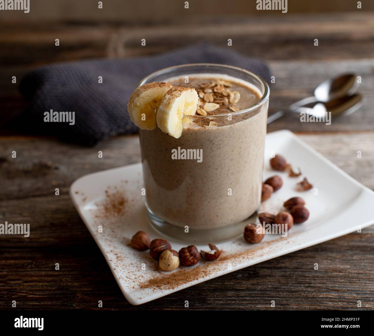 Protein-Smoothie aus Schokoladenmolkenpulver, Haferflocken, Bananen, Haselnüssen und Zimt. Stockfoto