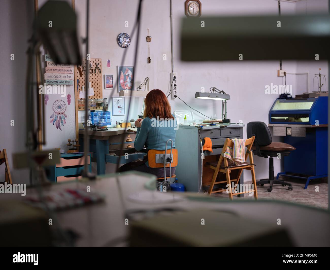 Eine Erwachsene Arbeiterin, die in ihrer Schmuckwerkstatt arbeitet und auf einer Werkbank sitzt Stockfoto