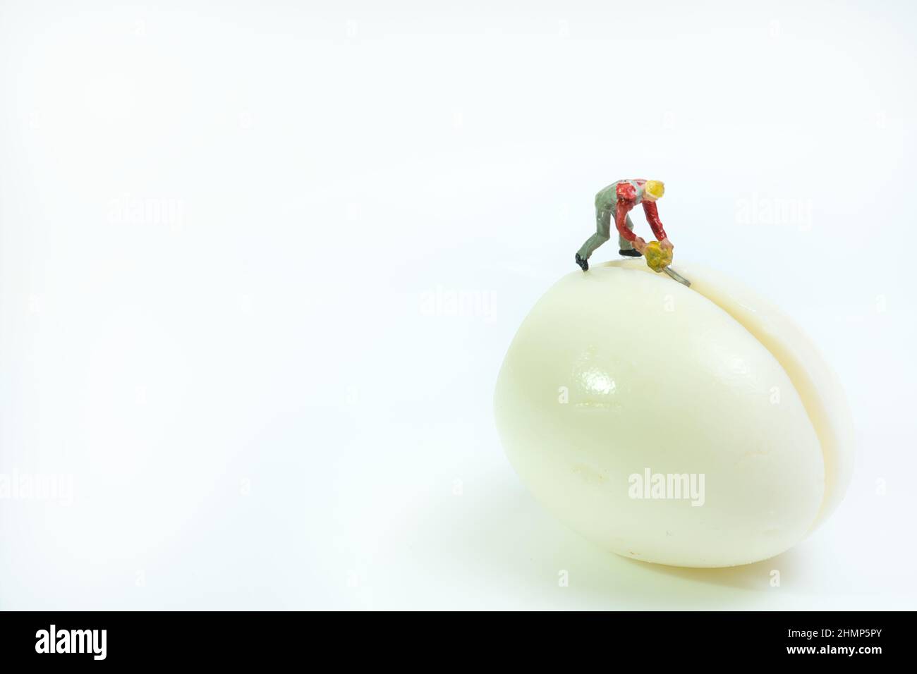 Ein Arbeiter mit einer Kettensäge steht auf einem gekochten Ei, um es zu halbieren Stockfoto