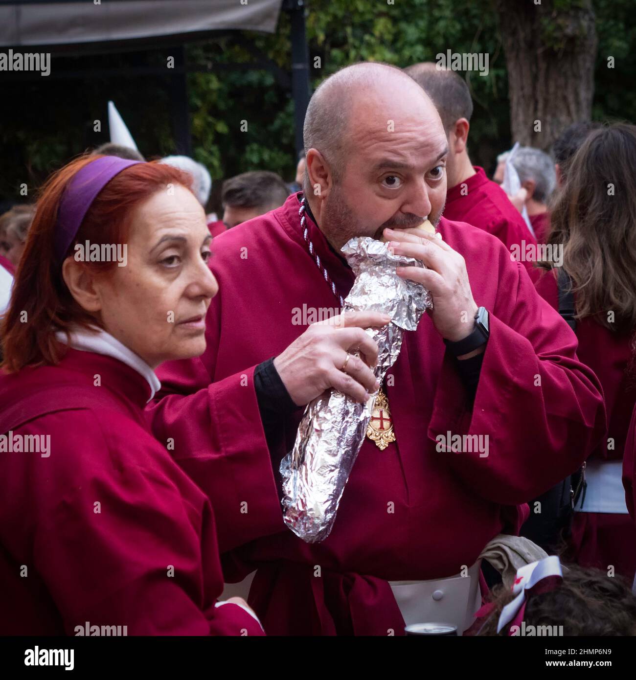 Cofrades ruhen sich während der Prozessionen der Karwoche in Cuenca aus, während sie ein Sandwich essen. Stockfoto