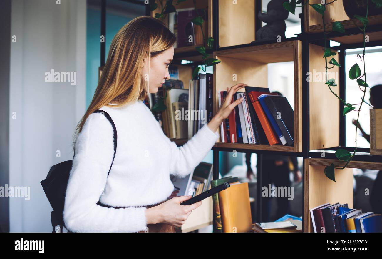 Ernsthafte weibliche Wahl Buch aus Bücherregal Stockfoto