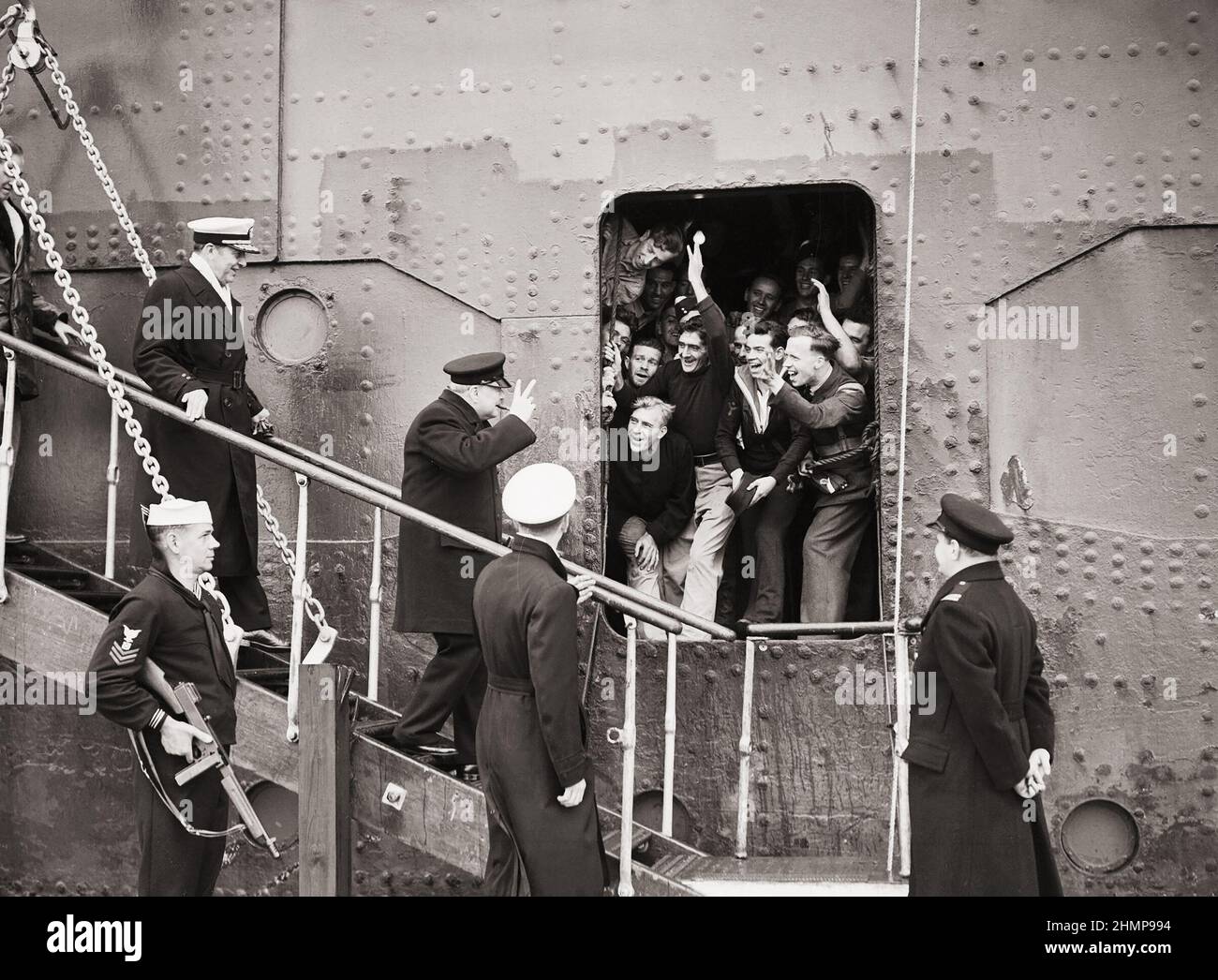Der Premierminister gibt das Siegeszeichen als Antwort auf die guten Wünsche der Matrosen, Flieger usw. an Bord, als er WW2 von der SS-KÖNIGIN MARY aussteigt Stockfoto