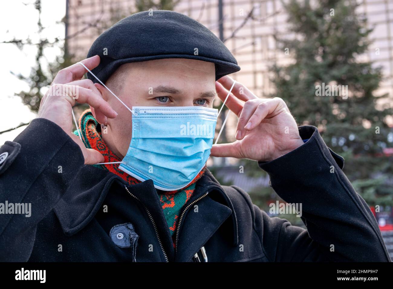 Ein junger Mann, der seine schützende Gesichtsmaske aufsetzt. Im Freien. Maßnahmen zum Schutz des Coronavirus. Stockfoto