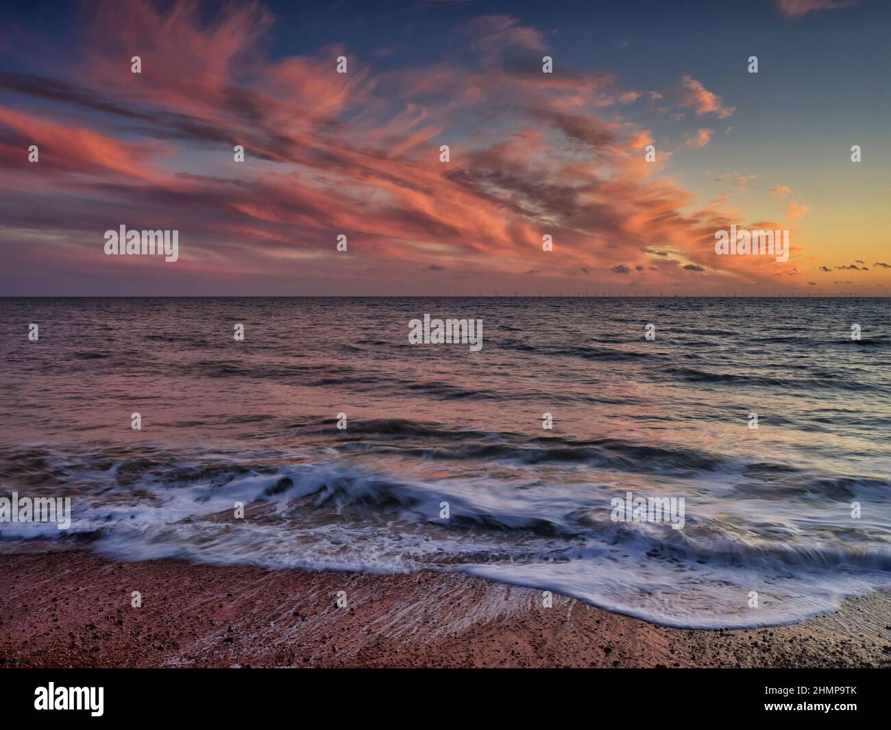 Eine minimalistische Aufnahme, die den Sonnenuntergang nach dem Sonnenuntergang und die Wellen am Brighton Beach für ein ultimatives ruhiges Gefühl darstellt. Stockfoto