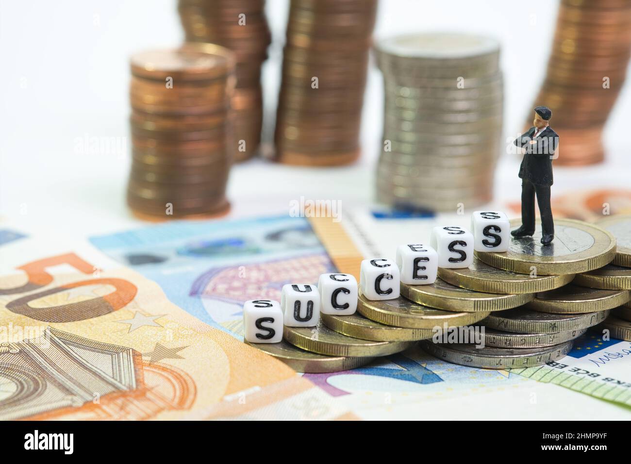 Ein Manager steht auf einem Münzturm, der Aufstieg wird als Erfolg bezeichnet. Konzept: Weiterentwicklung in der Finanzwelt Stockfoto