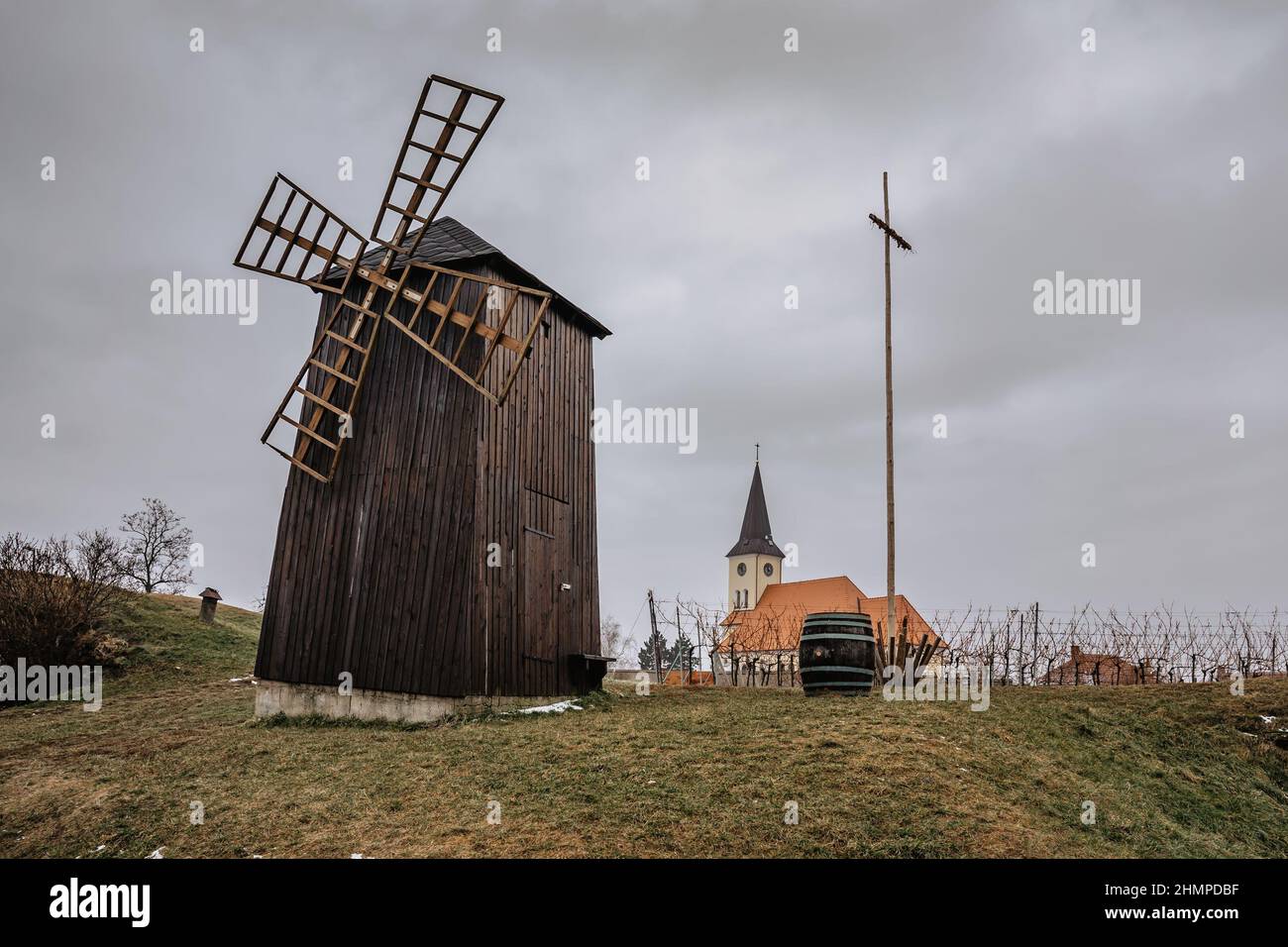 Vrbice, Weindorf in Mähren, Tschechische Republik, mit traditioneller Holzwindmühle und Weinfass, Kirche im Hintergrund.Weinprobe, lokale Folklore.Tschechisch Stockfoto