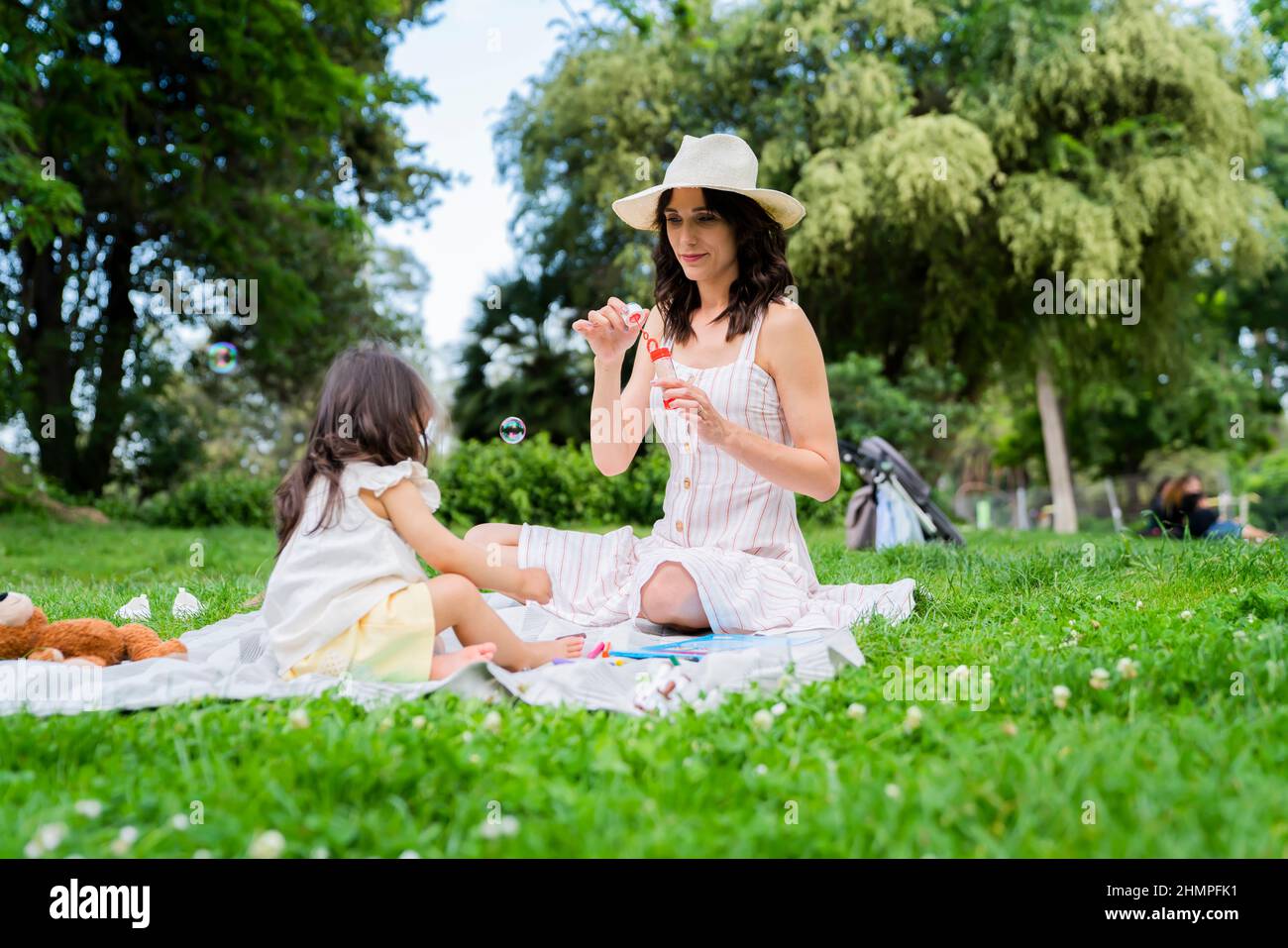 Junge Mama bläst Blasen für kleine Tochter im Park Stockfoto