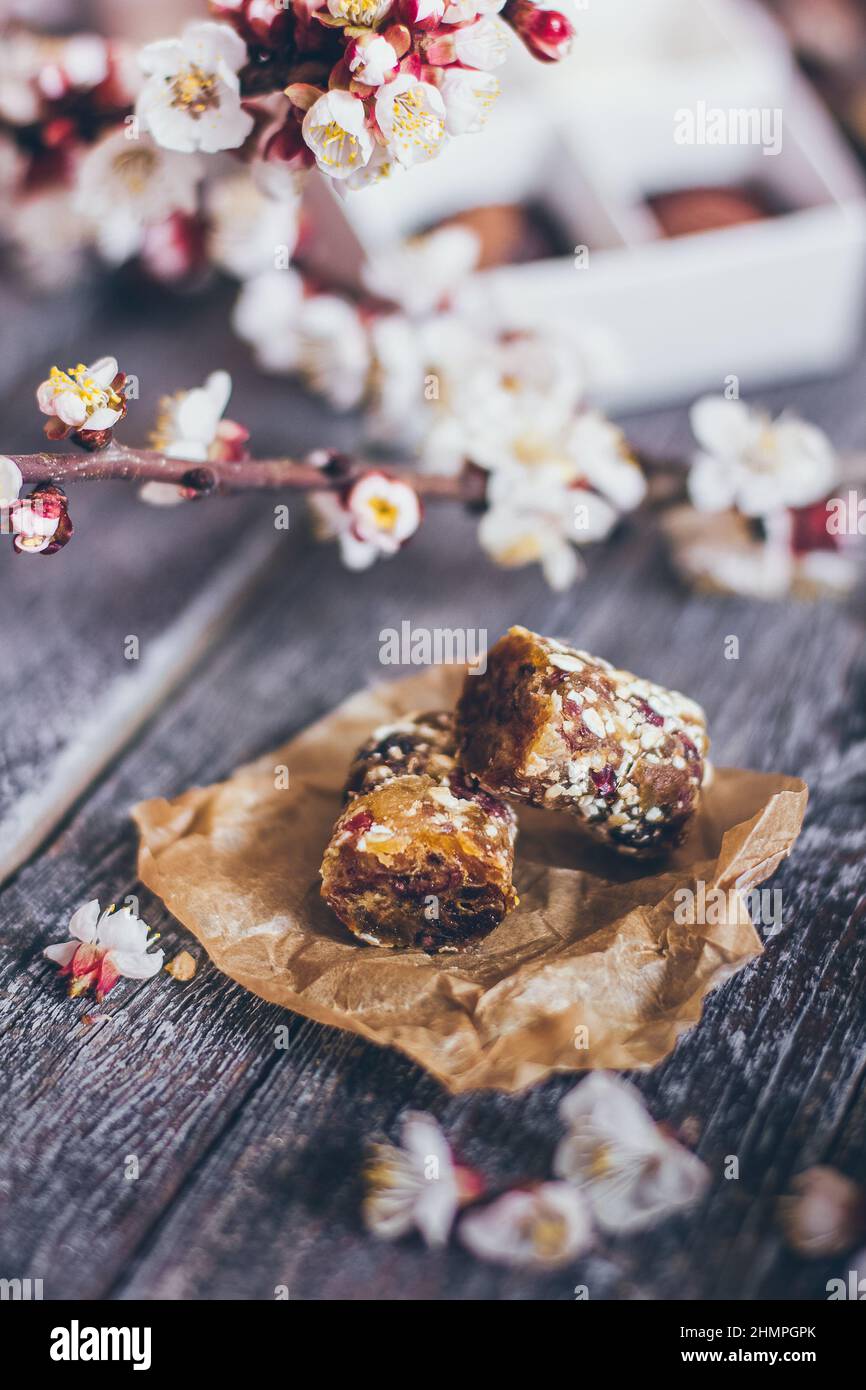 Frühling Kollektion von handgefertigten Schokolade Bonbons Süßigkeiten und Kirschblüten Dekoration auf rustikalem Holzhintergrund Stockfoto
