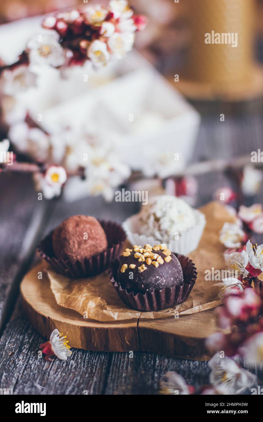 Frühling Kollektion von handgefertigten Schokolade Bonbons Süßigkeiten und Kirschblüten Dekoration auf rustikalem Holzhintergrund Stockfoto