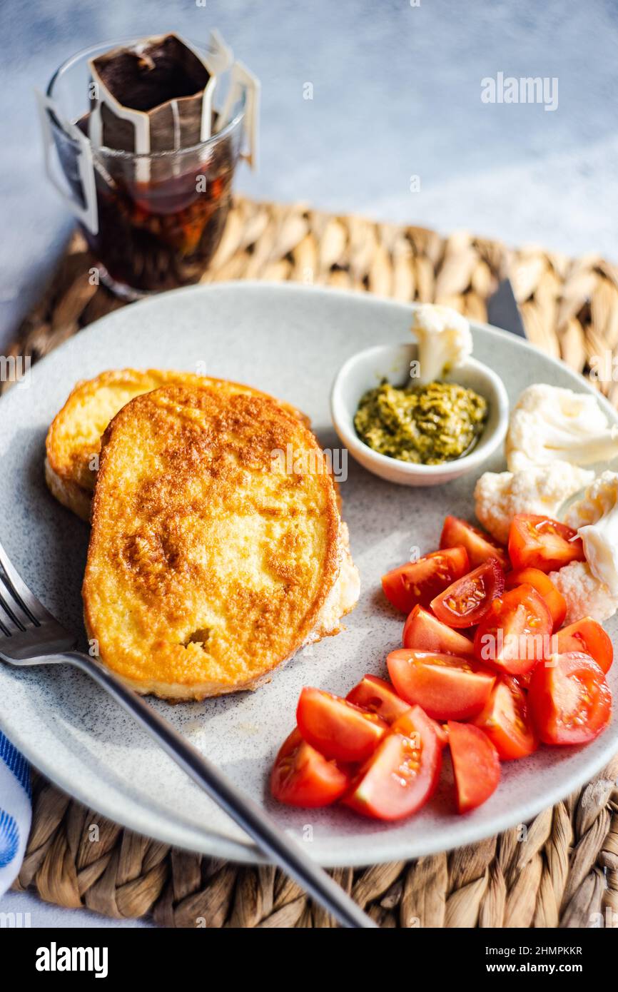 Französischer Toast, Pesto, Tomate, Blumenkohl und ein Glas schwarzen Kaffee Stockfoto