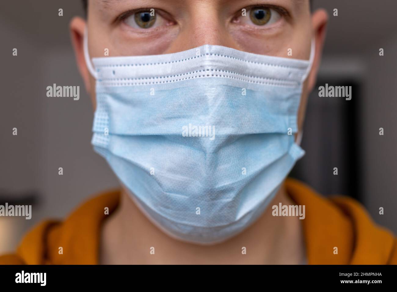 Mann mit traurigen Augen in blauer Gesichtsmaske Stockfoto