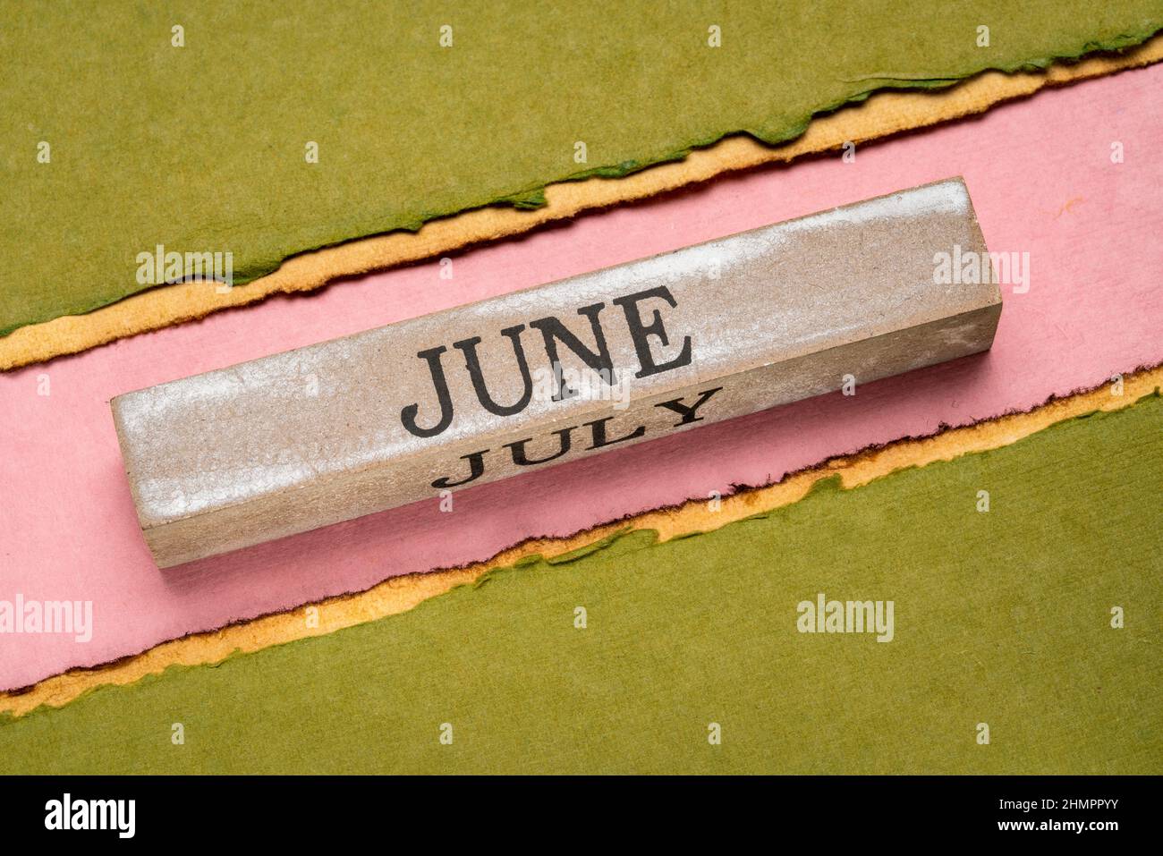 Juni Text auf grunge Holzblock gegen handgemachtes Lapppapier in rosa, orange und grünen Tönen, Kalenderkonzept Stockfoto