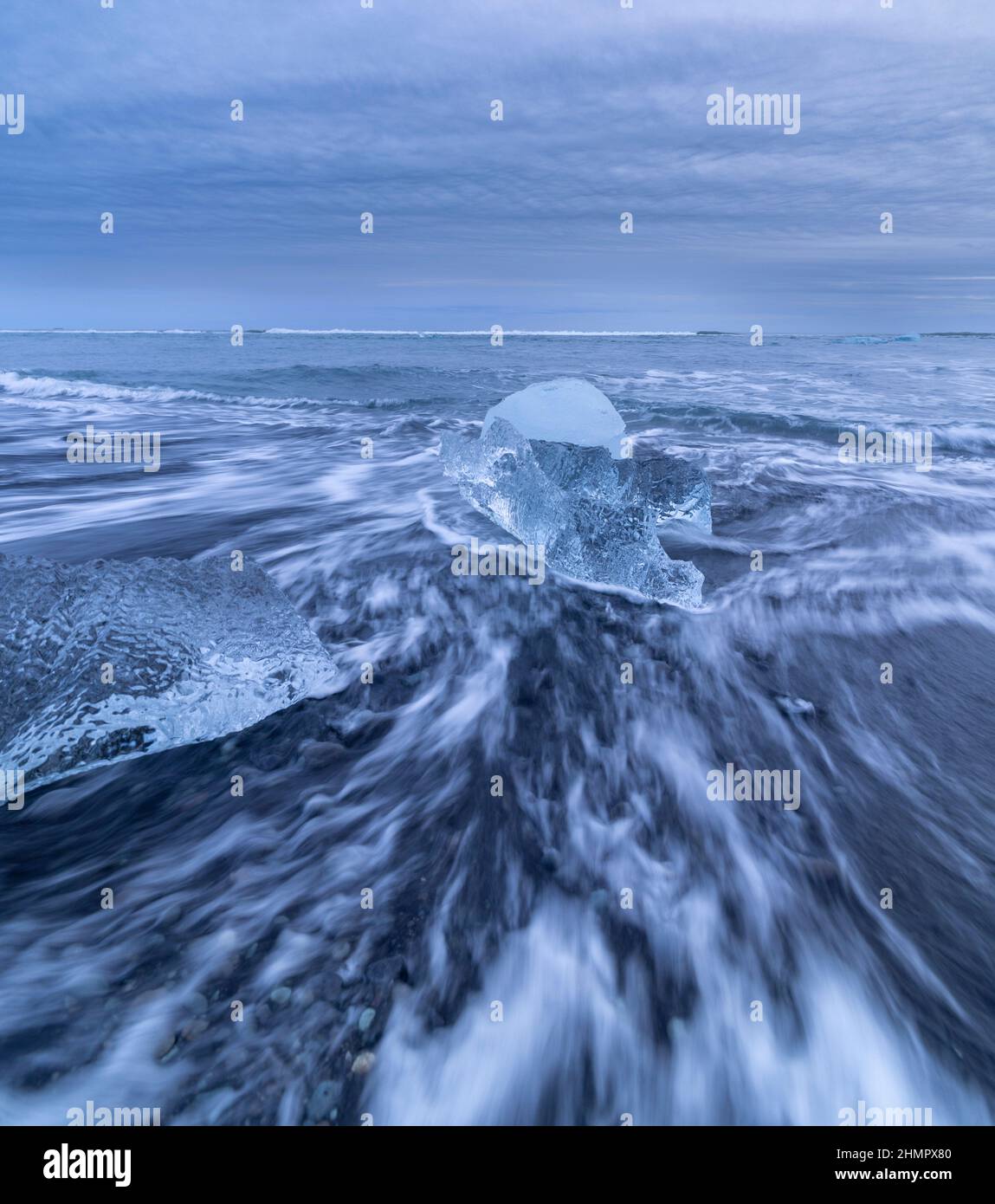 Kleine Eisblöcke und ankommende Wellen am Diamond Beach mit schwarzem Sand, Breidamerkursandur, Island Stockfoto