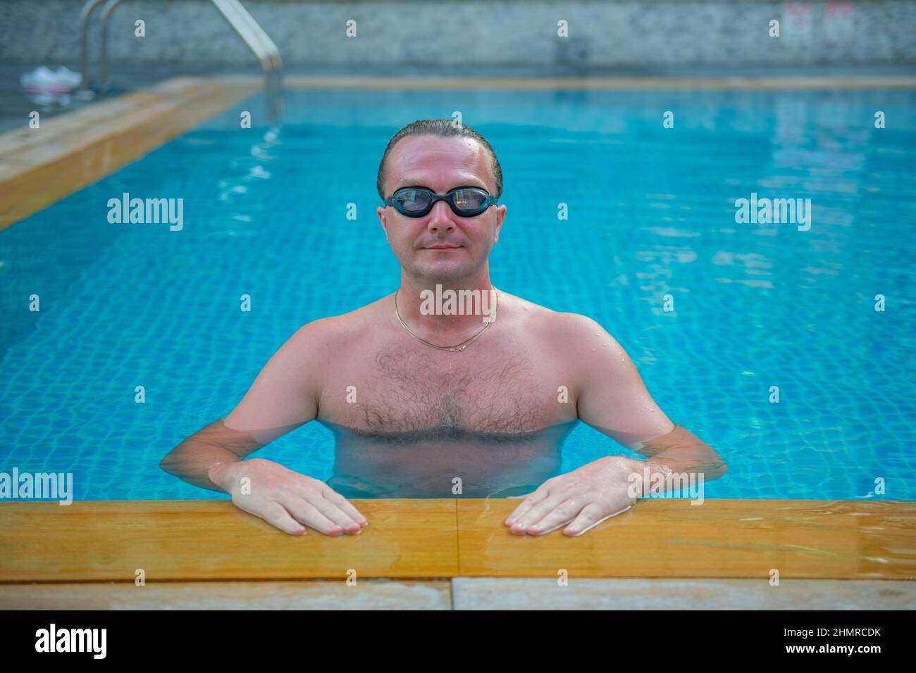 Ein starker Typ mit Brille schwimmt in einem großen Pool Stockfoto
