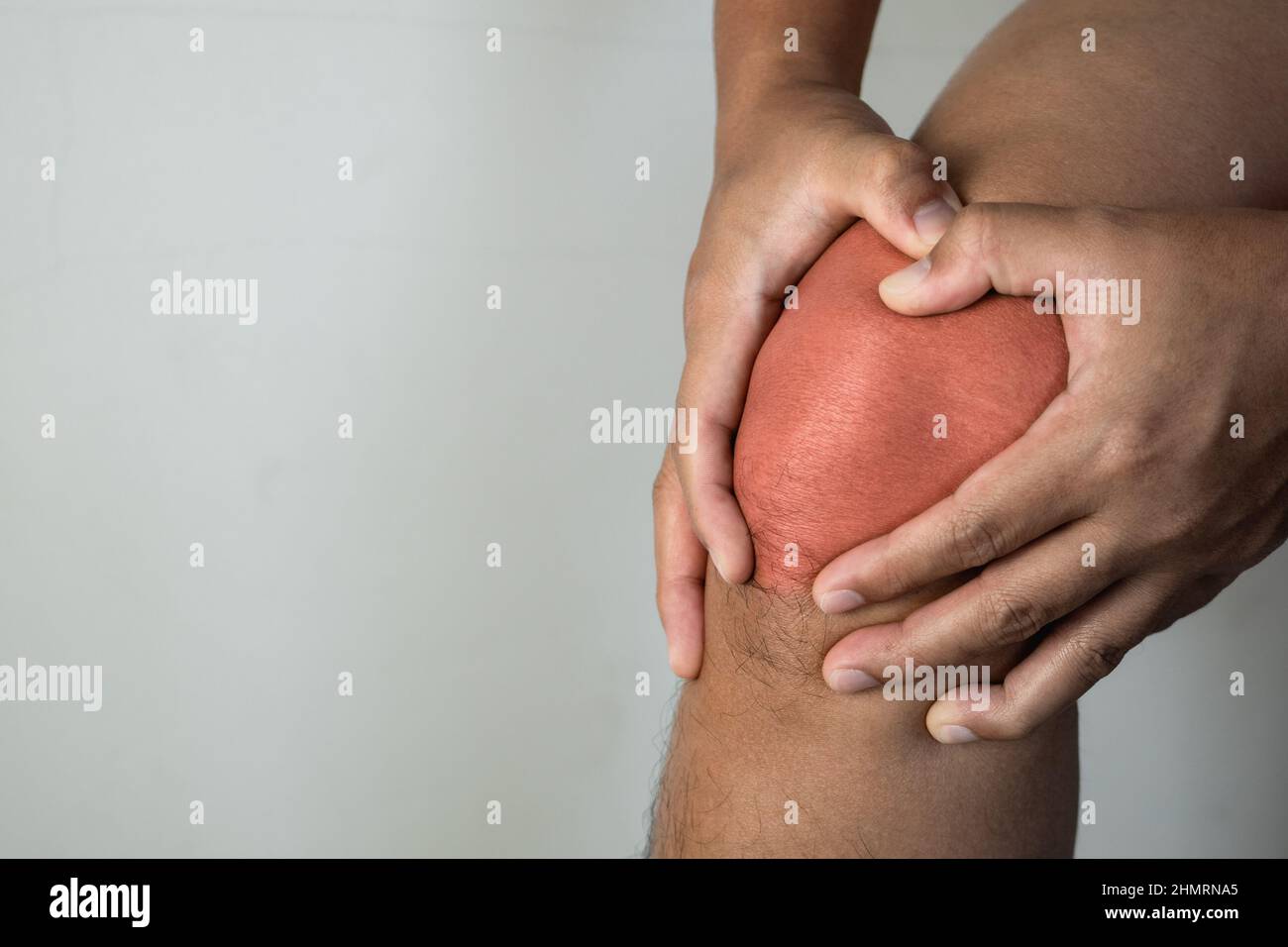 Der Mann hält seinen Schmerzpunkt am Kniegelenk. Der rote Punkt zeigt die Verletzungsposition an. Nahaufnahme von vorne. Stockfoto