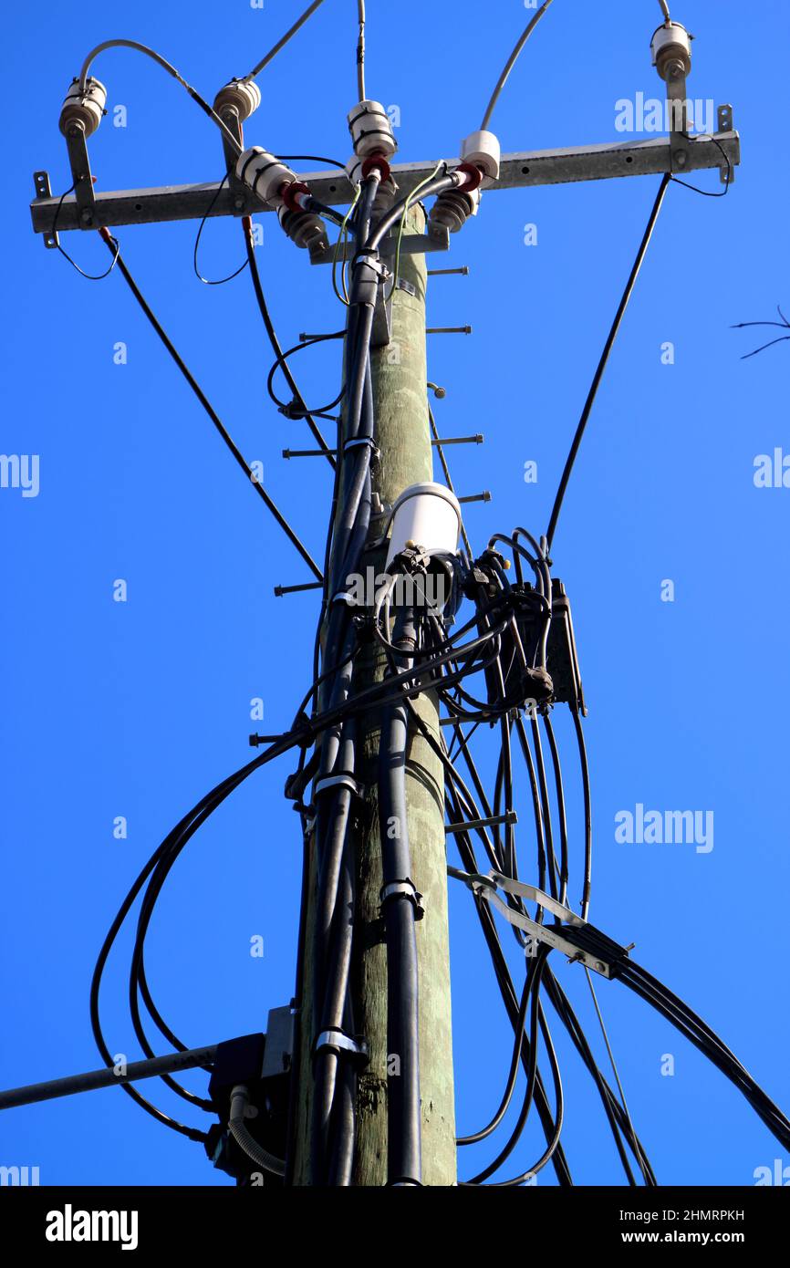 Aufnahme eines alten hölzernen Telefons und einer Stromleitung in einem Winkel von oben gegen den blauen Himmel in Australien Stockfoto