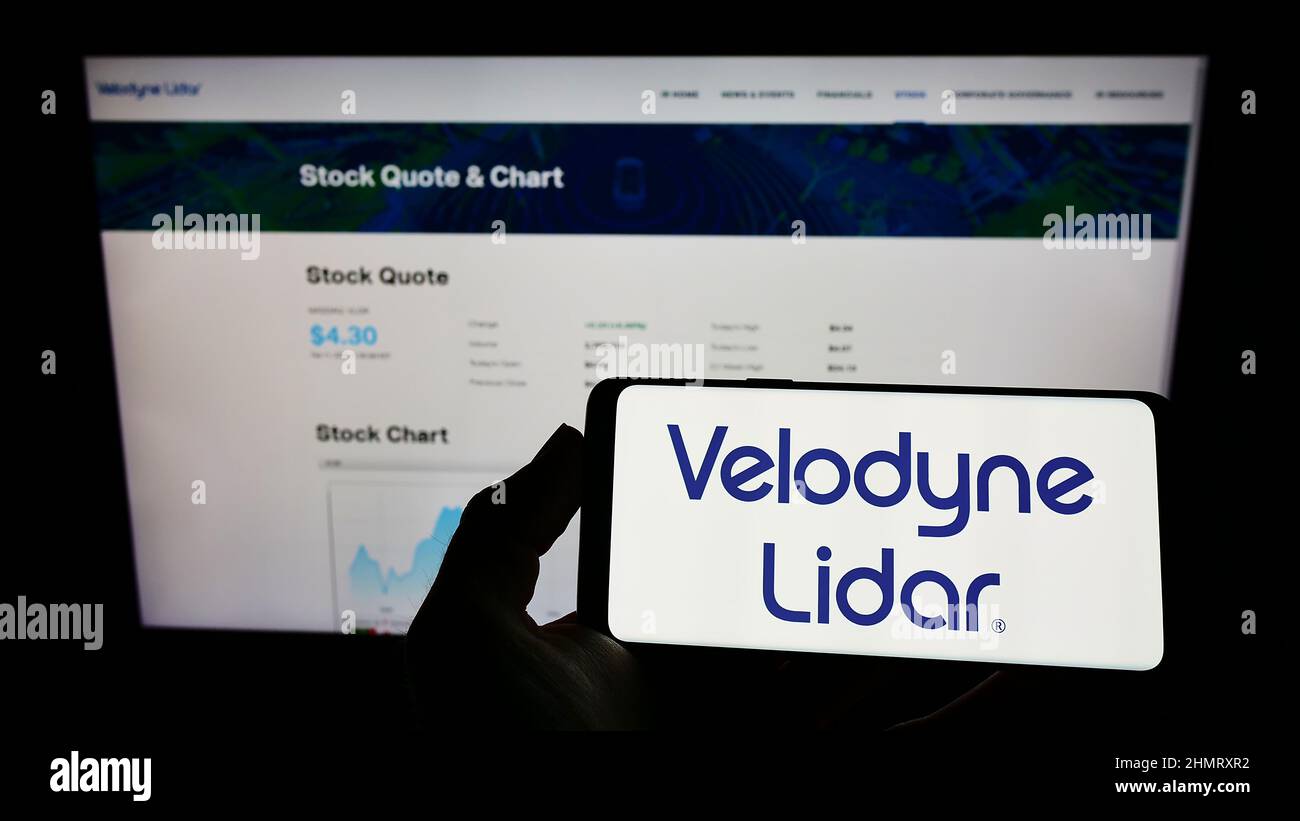 Person, die das Mobiltelefon mit dem Logo des amerikanischen Technologieunternehmens Velodyne Lidar Inc. Auf dem Bildschirm vor der Webseite hält. Konzentrieren Sie sich auf die Telefonanzeige. Stockfoto