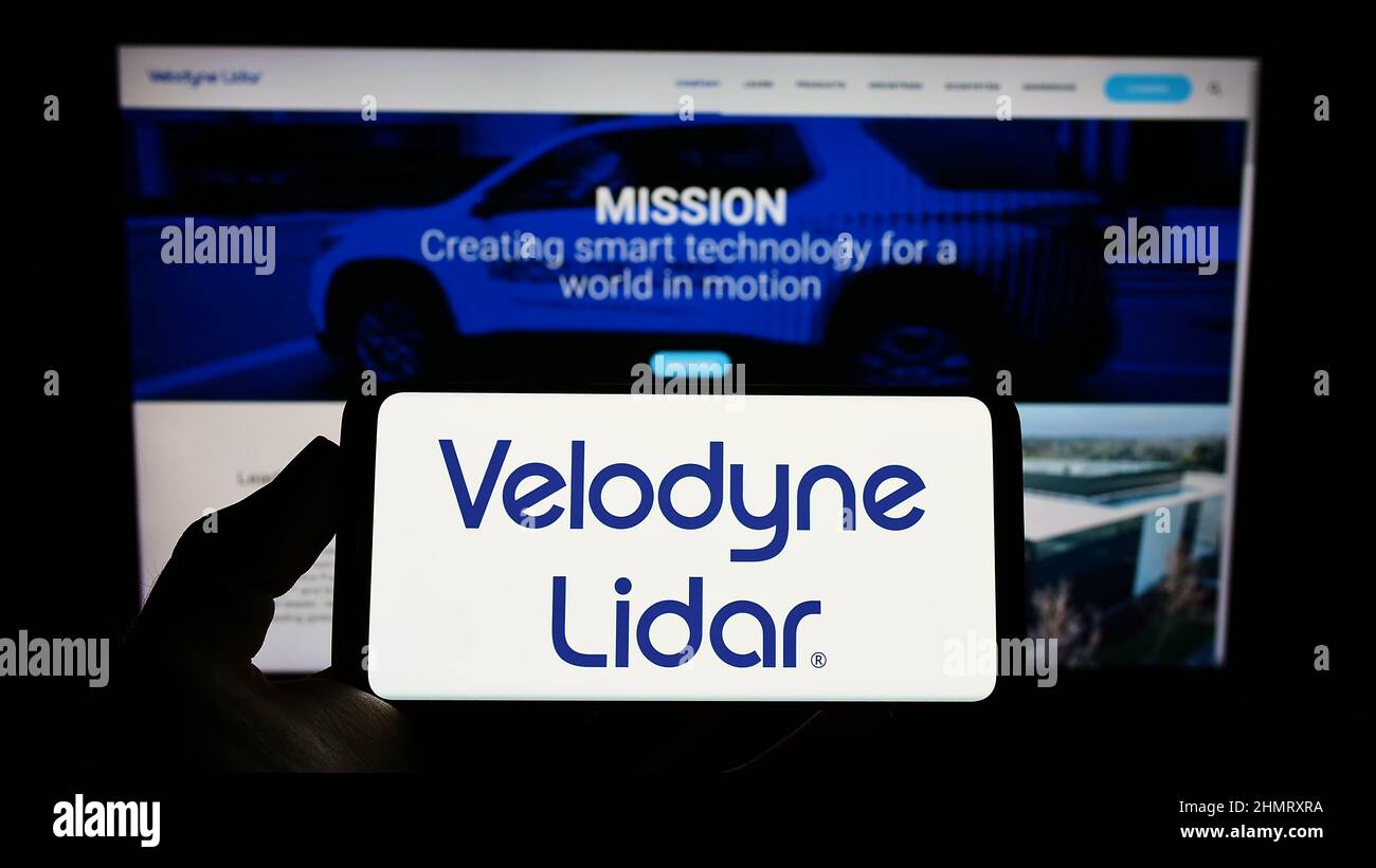 Person, die das Smartphone mit dem Logo des US-Technologieunternehmens Velodyne Lidar Inc. Auf dem Bildschirm vor der Website hält. Konzentrieren Sie sich auf die Telefonanzeige. Stockfoto