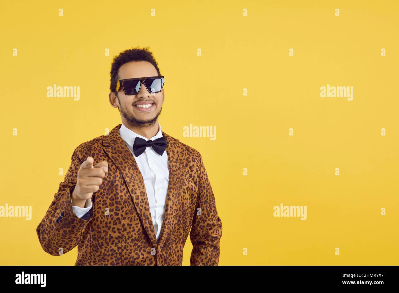 Fröhlicher schwarzer Kerl in coolen Brillen und funky Anzug zeigt Finger auf Kamera auf Kopierraum Hintergrund Stockfoto